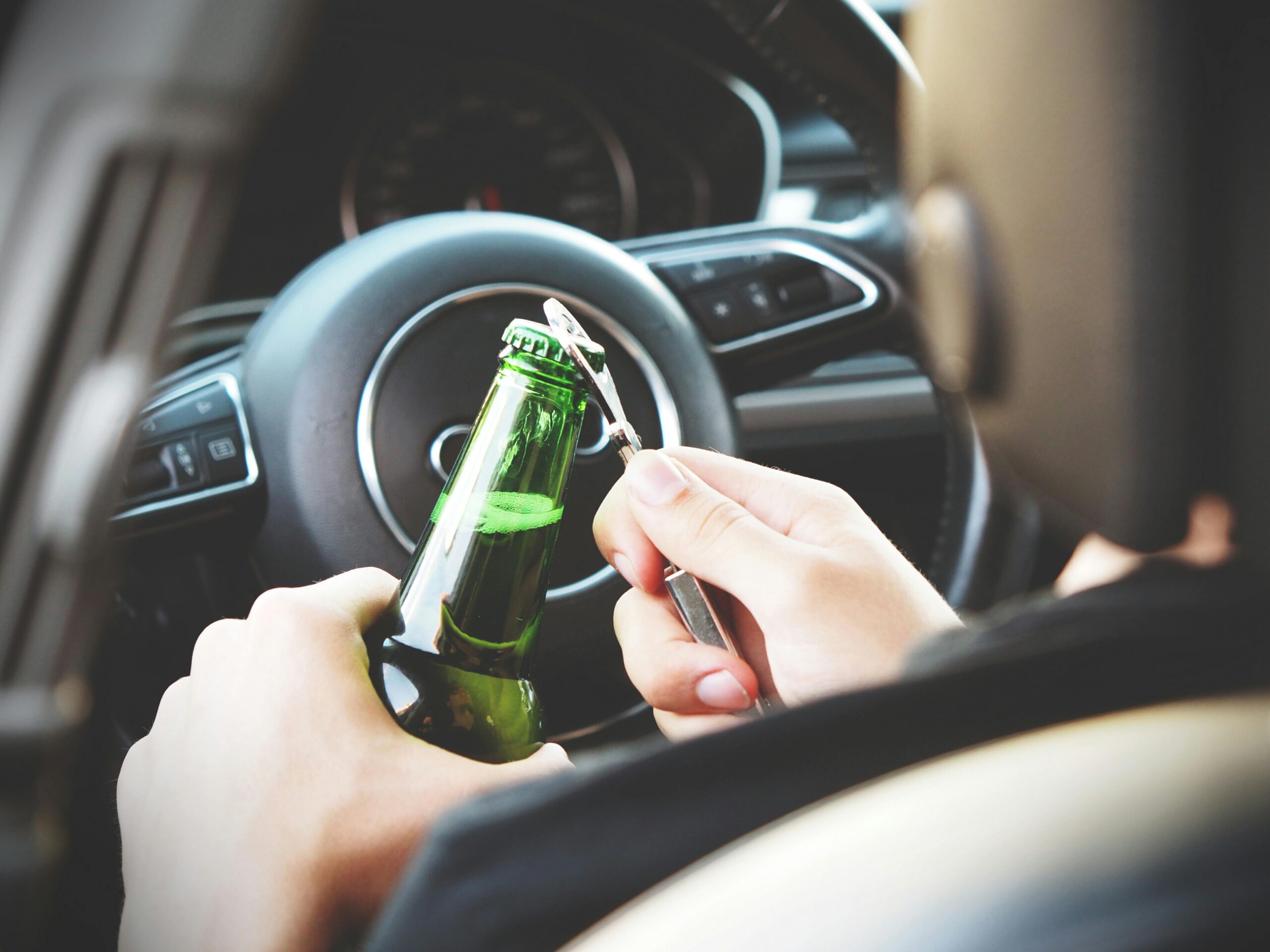 Driver opening beer bottle with opener inside car
